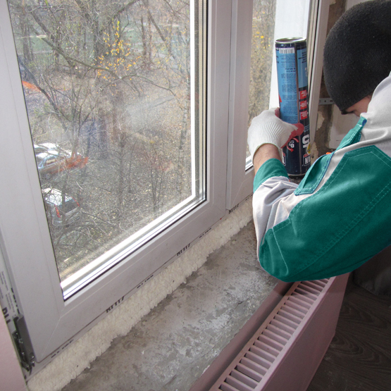 Монтажник выполняет монтаж окна из металлопластикового профиля (ПВХ)