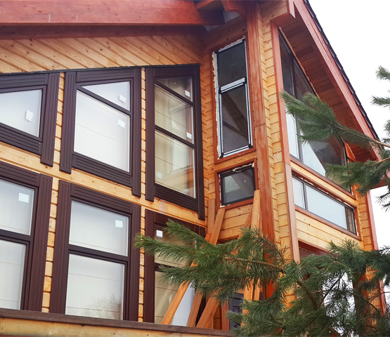 Один из вариантов остекления деревянного коттеджа — алюминиевые окна с декоративными нащельниками
